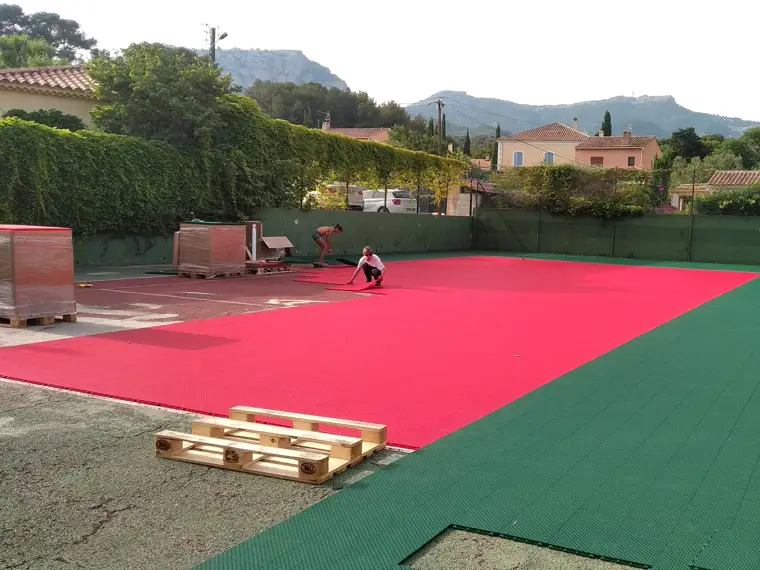 Pose de dalles sportives sur court de tennis après ragréage ponctuel