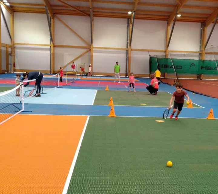 Terrain de jeux de raquettes avec dalles sportives sur court de tennis avec enfants en action